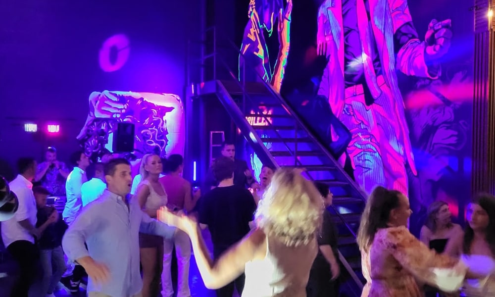 Packed Dancefloor at Ed’s Place – Hallam’s Premier Event Venue People dancing in a vibrant club setting with neon wall art and LED lighting at Ed’s Place in Hallam