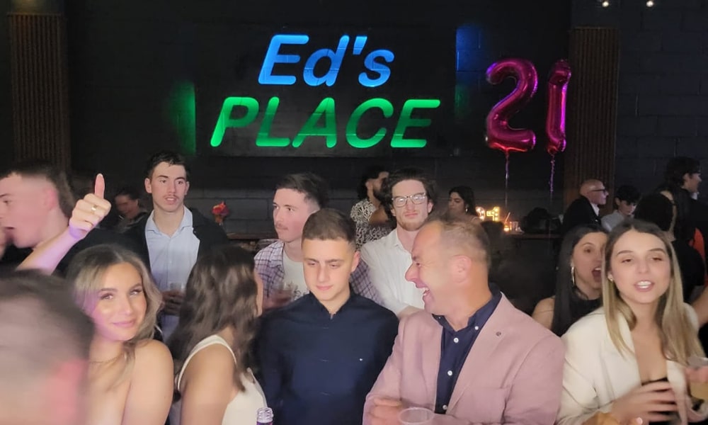 21st Birthday Celebration at Ed’s Place – Event Venue in Hallam VIC Group of people celebrating a 21st birthday at Ed’s Place venue in Hallam with neon signage in the background